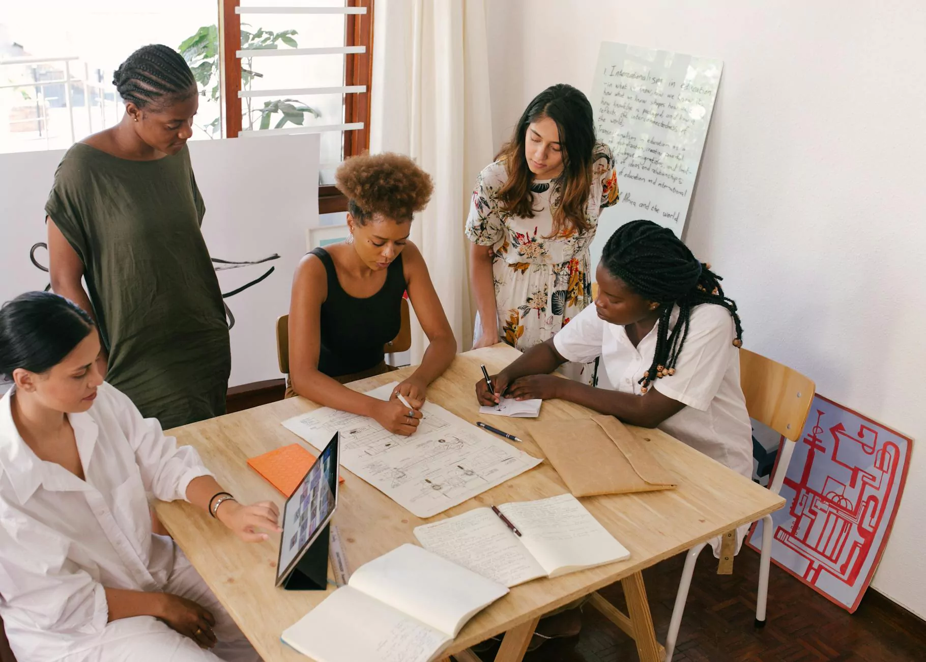 A group sharing notes and reviewing ideas around a work table